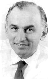 A 'selfie' photograph of a smiling, balding man, in a shirt and tie.