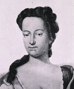 An 18th century lithographic headshot portrait of a woman with long dark hair in a low-cut dress.