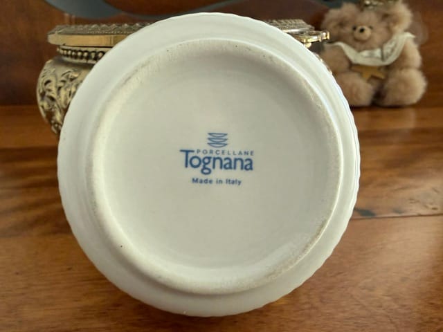 A porcelain ashtray, white ground, with gilt edges, purple grapes, green leaves and brown stems, and gold lettering.