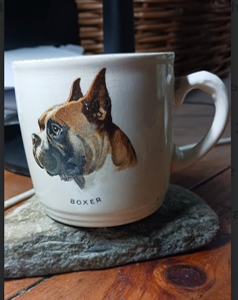 A white coffee mug featuring the image of a fawn dog with cropped ears and a black mask, the word BOXER printed beneath him in small capitals